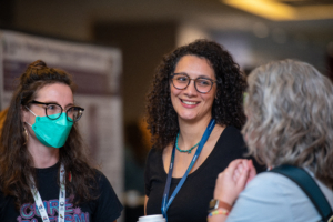 A group of three ladies at ATIA 2024 network and chat around the poster session area.