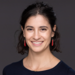 Picture of Amanda Lazar wearing a black top with a gold necklace and red earrings.