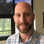 Picture of Matthew Newton wearing a blue, white, and orange plaid shirt.