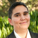 Picture of Rachel Sessler Trinkowsky wearing a gray blazer over a white collared shirt.
