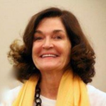 Picture of Sara Czaja wearing a white top with a black chain necklace and a yellow scarf.
