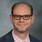 Picture of Walter Boot wearing a pink button up shirt under a gray sports coat.